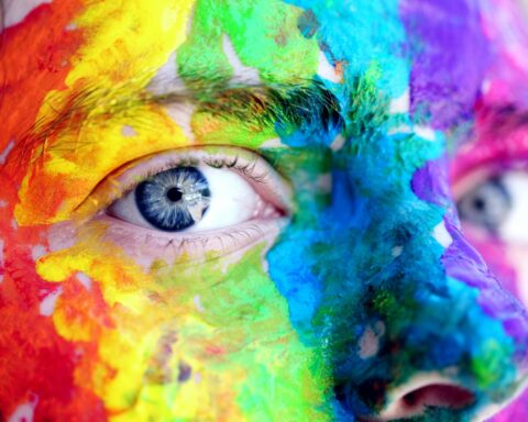 Close-up of a person with colorful rainbow face paint, symbolizing LGBT pride and expression.