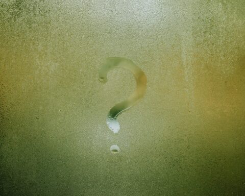 A question mark drawn on foggy glass, evoking curiosity and mystery.
