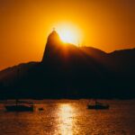 Silhouette of Sugarloaf Mountain at sunset with boats and calm sea in Rio de Janeiro, Brazil.