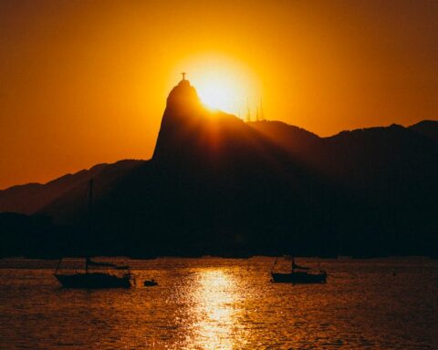 Silhouette of Sugarloaf Mountain at sunset with boats and calm sea in Rio de Janeiro, Brazil.